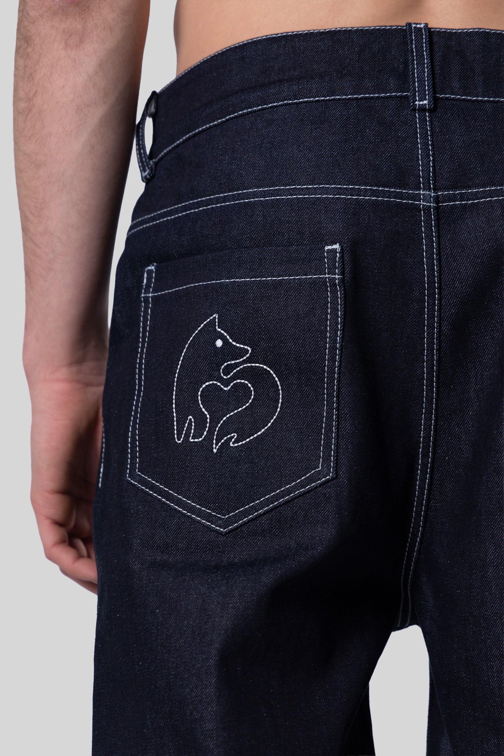 Close-up of fox logo embroidery on back pocket of indigo 4Front jeans