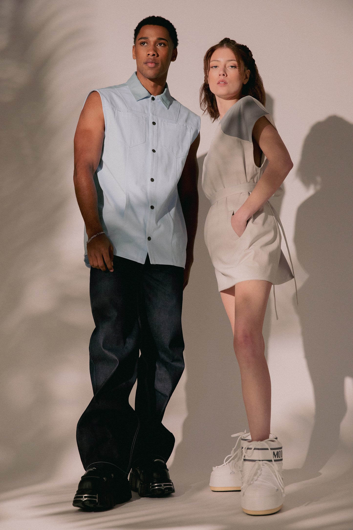 [card:men-primary][card:all-primary] Male model wearing 4NML 4Front Jean in indigo Candiani raw denim and Blue Collar Vest, standing next to female model wearing Chameleon Dress