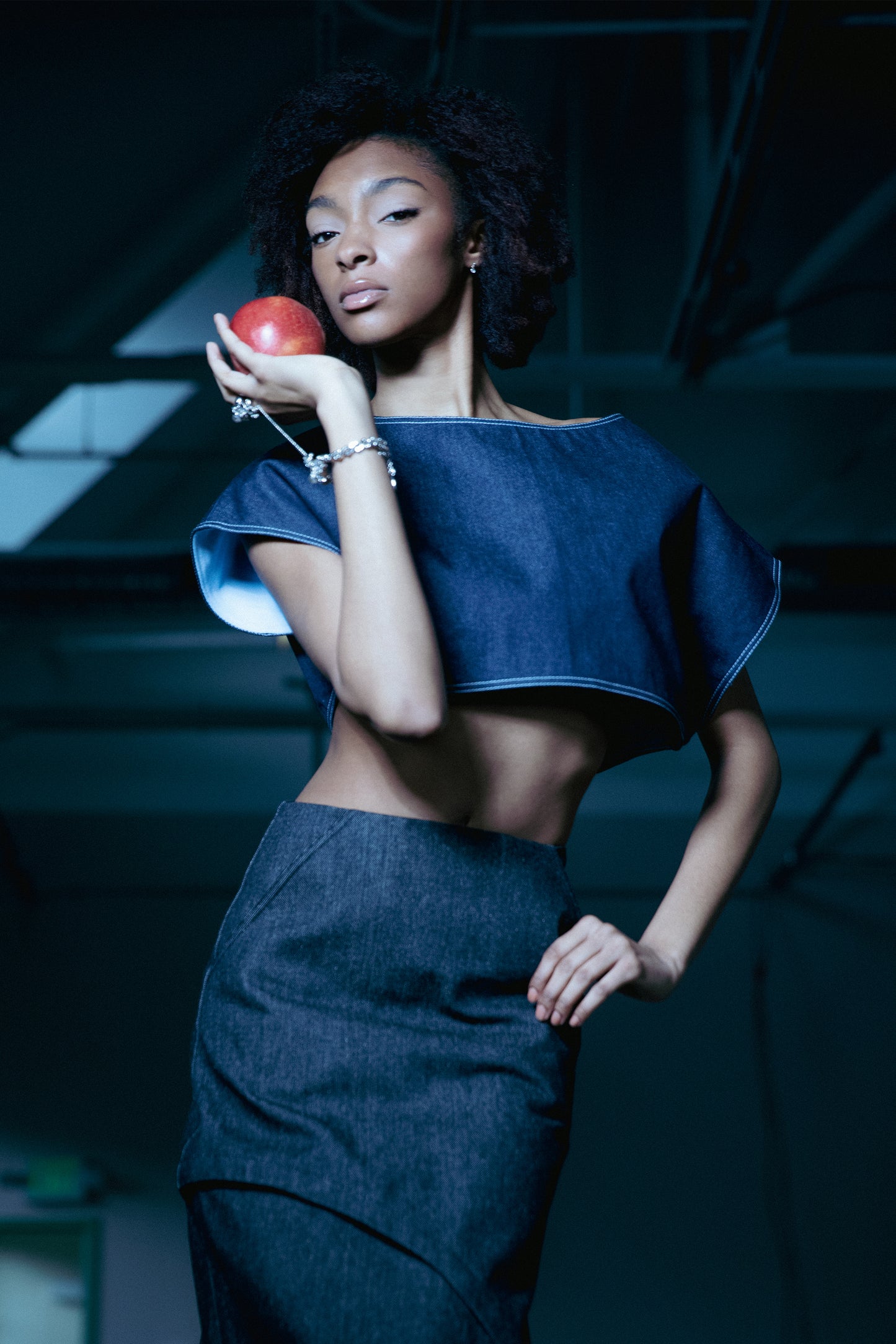 [card:women-primary][card:all-primary] Model wearing 4NML Fly Girl crop top in indigo Candiani raw denim, asymmetric off-shoulder design