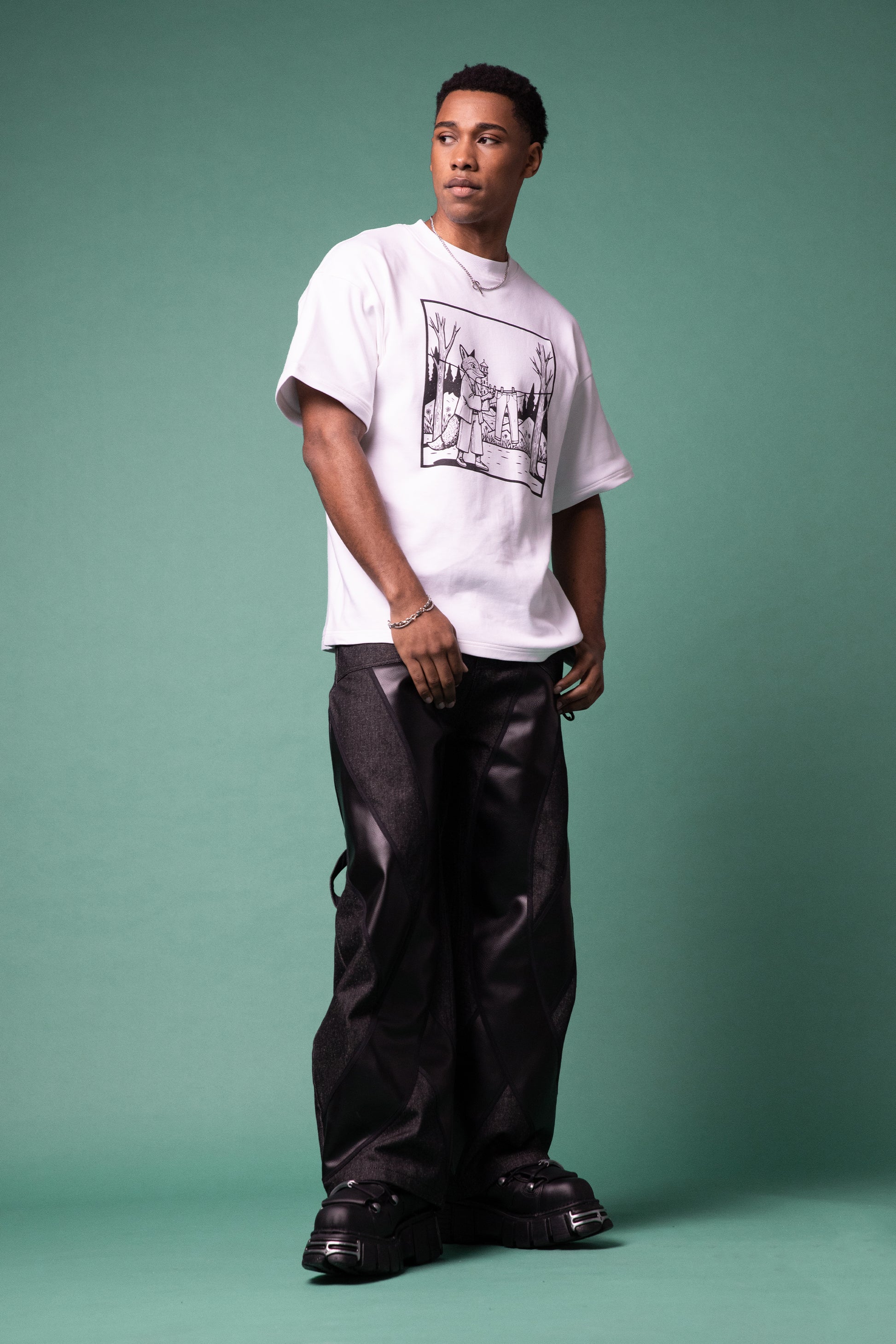 [card:men-primary][card:all-primary] Model standing in white Supima cotton Lineage Tee with black graphic and 4NML Bloom Jean in carbon Candiani raw denim with black AppleSkin panels, full body