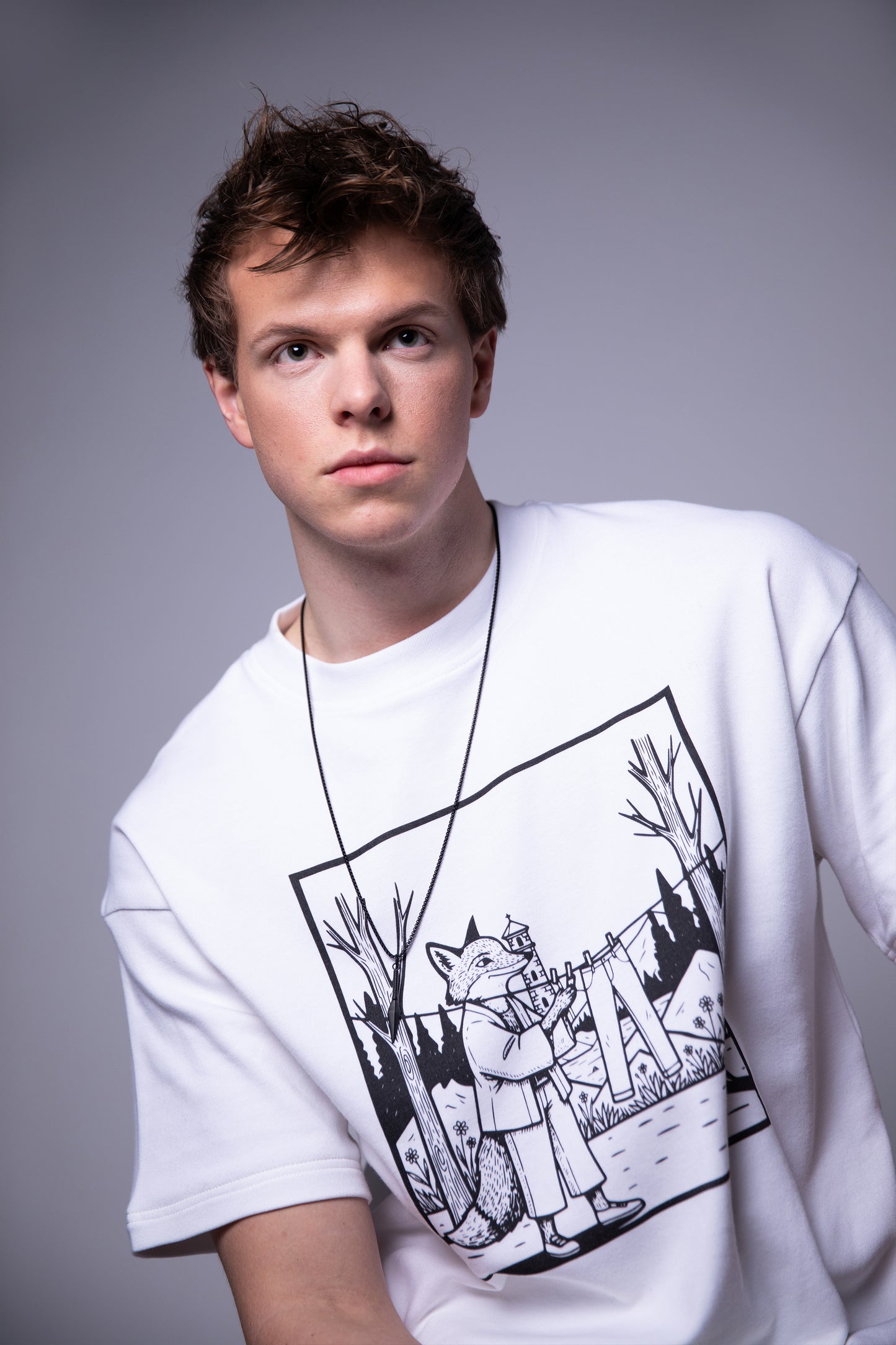[card:men-primary][card:all-primary] Model wearing 4NML Men’s Lineage Tee in white Supima cotton with black fox illustration