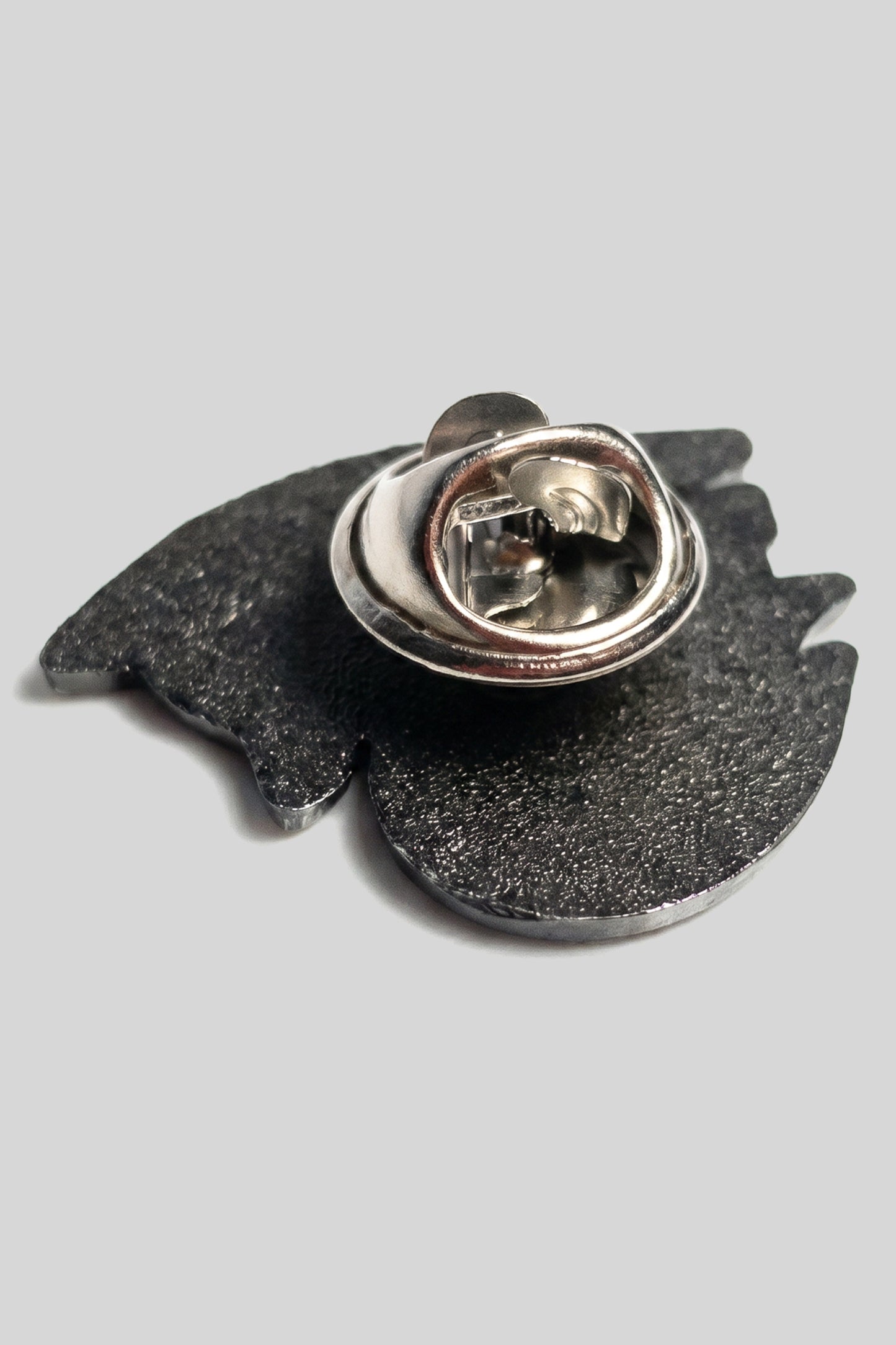 Back of silver die-struck 4NML logo pin