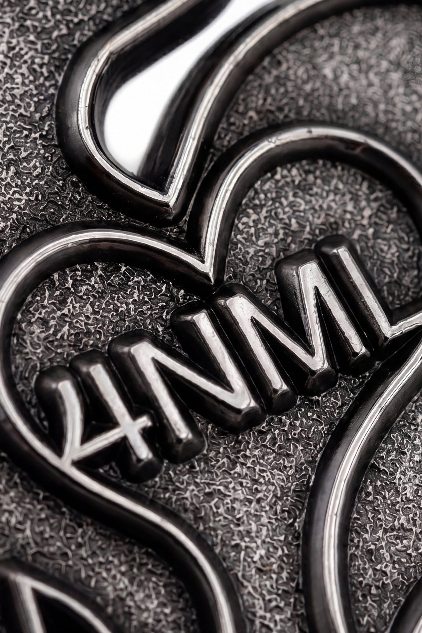 Close up photo of silver die-struck 4NML logo pin, showing details