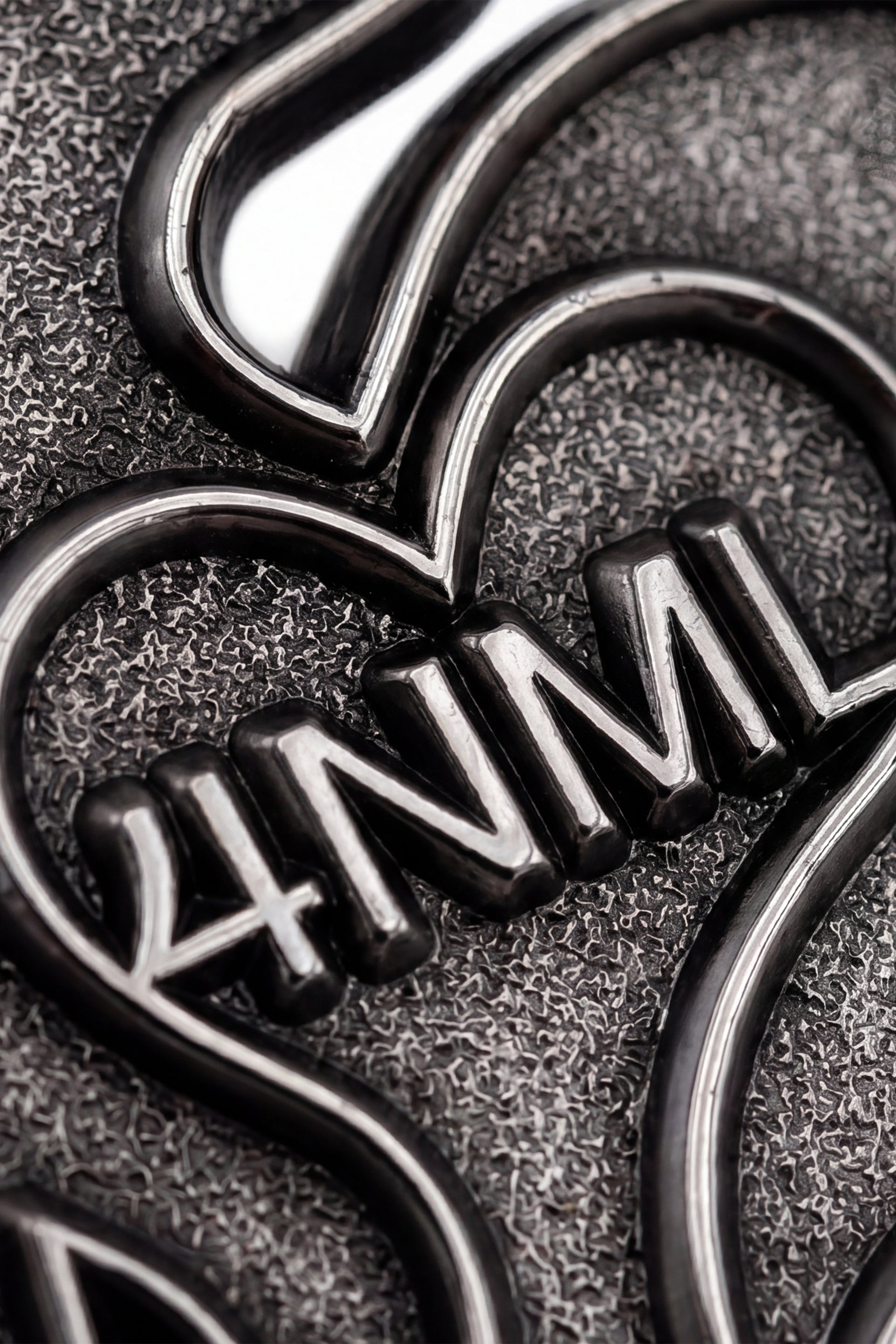 Close up photo of silver die-struck 4NML logo pin, showing details
