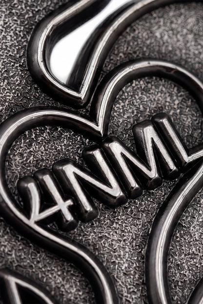 Close up photo of silver die-struck 4NML logo pin, showing details