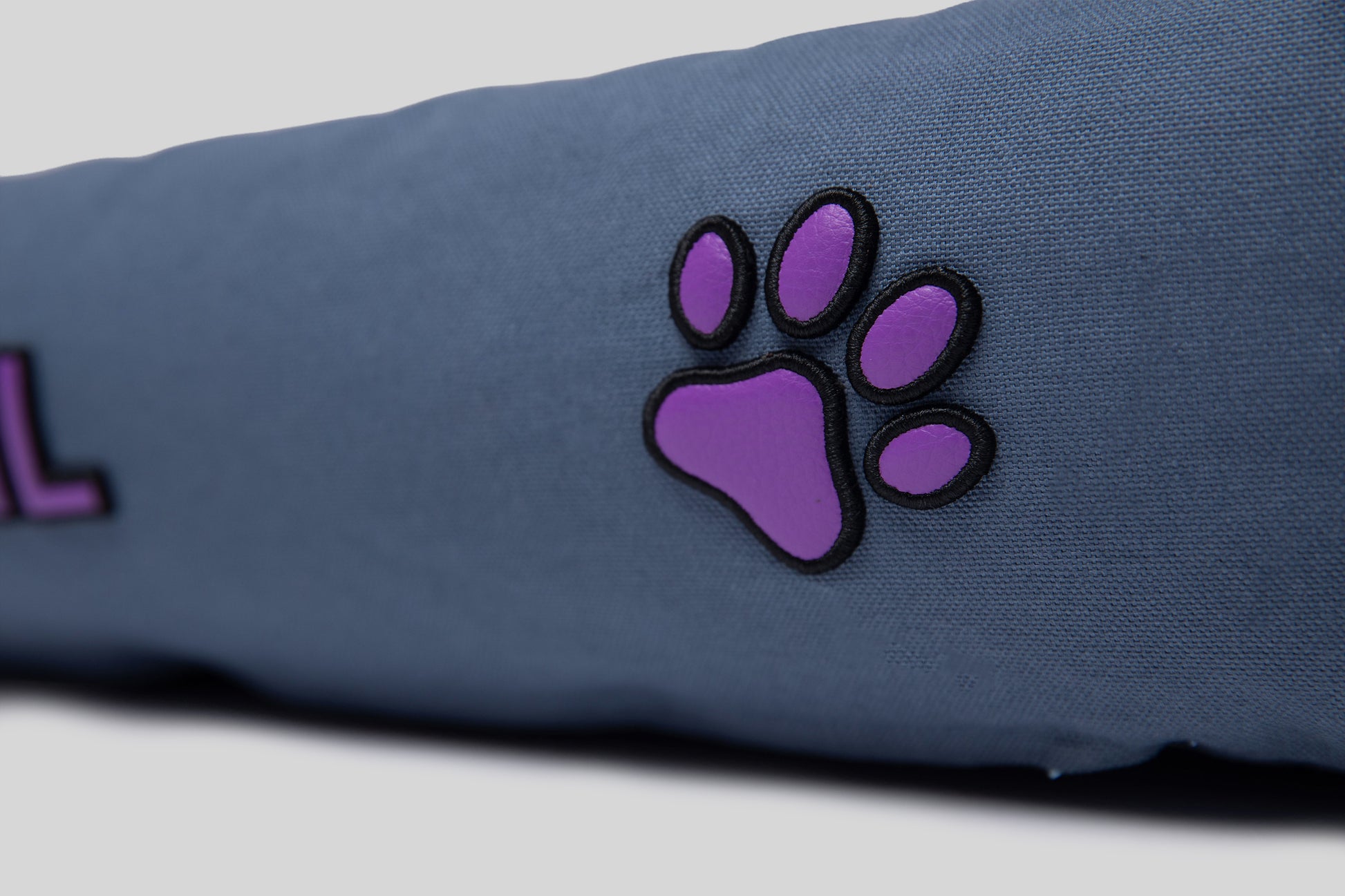 Close-up of lavender AppleSkin paw embroidery on blue canvas cotton pet bed