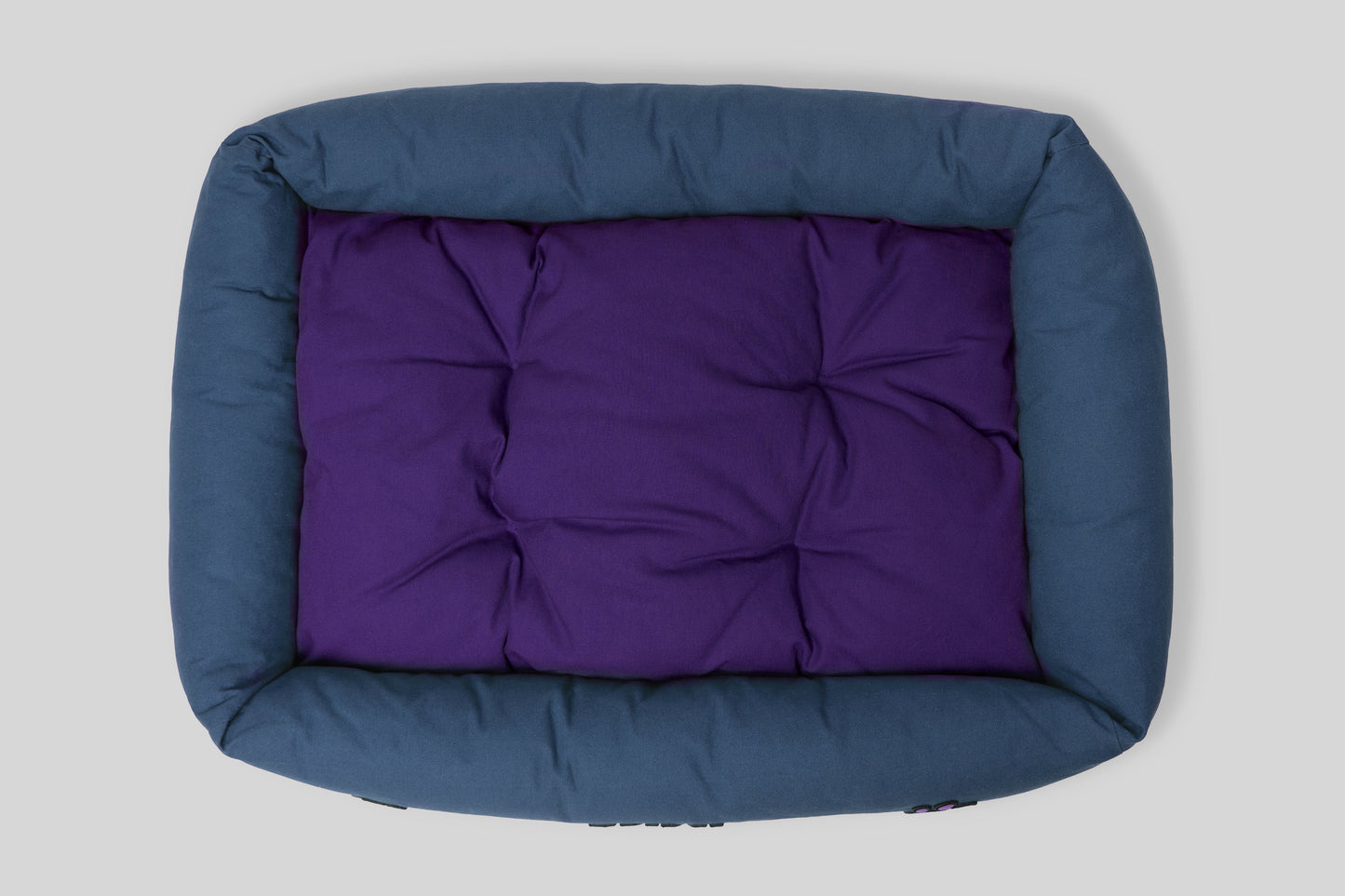 Top view of canvas cotton pet bed with tufted cushion, blue and purple colorway