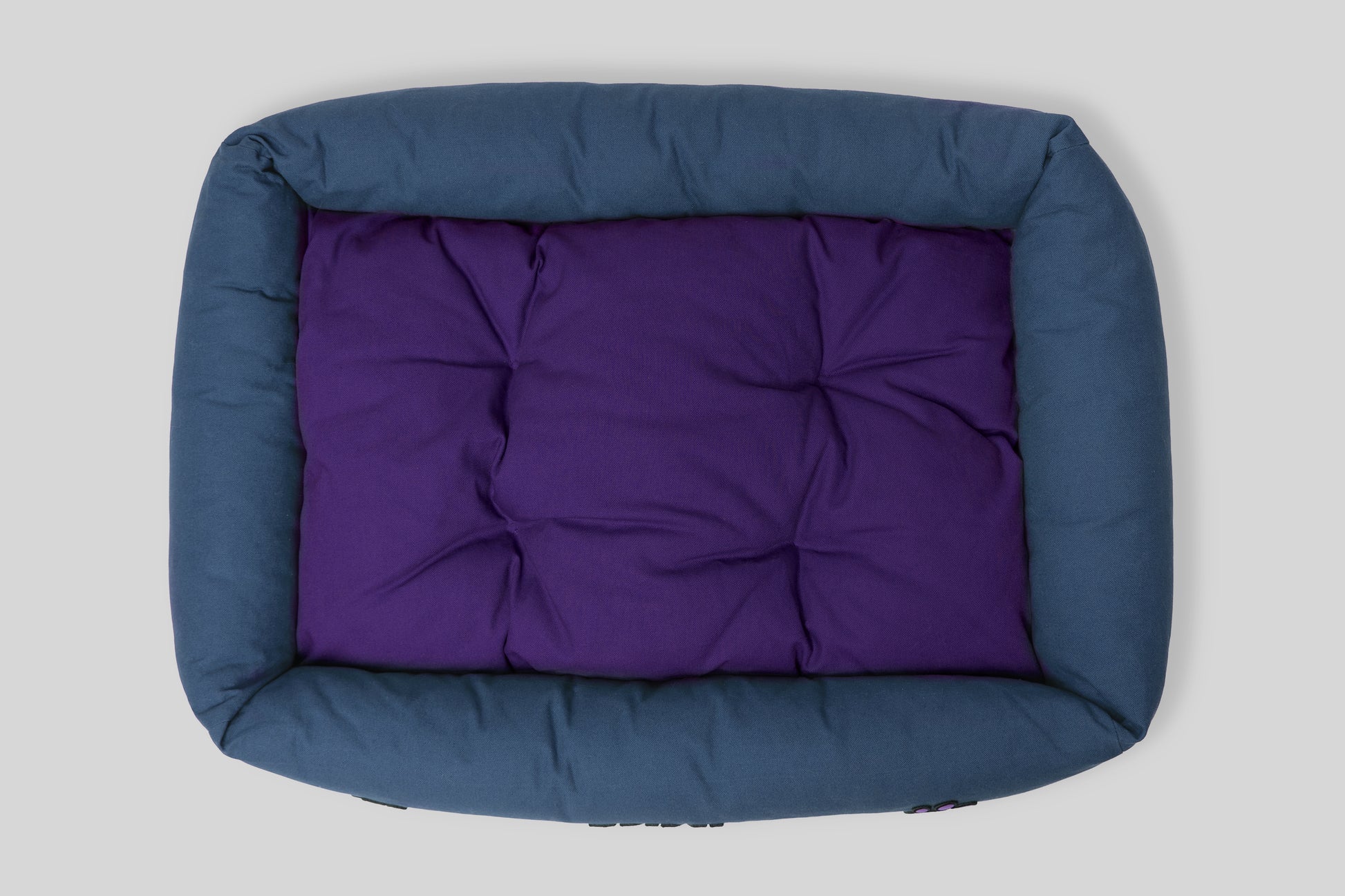 Top view of canvas cotton pet bed with tufted cushion, blue and purple colorway