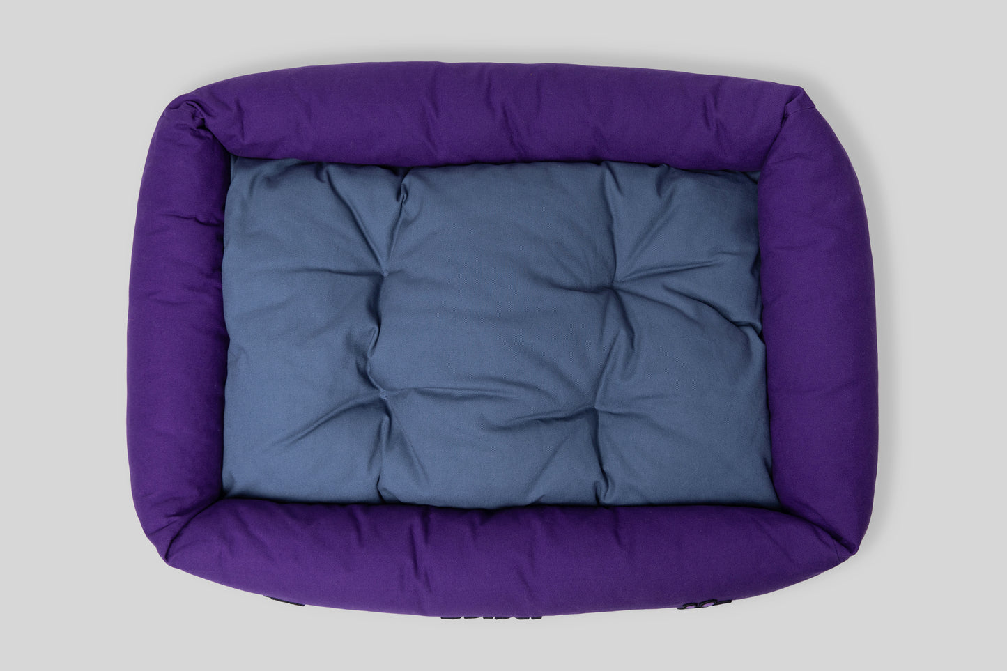 Top view of canvas cotton pet bed with tufted cushion, purple and blue colorway