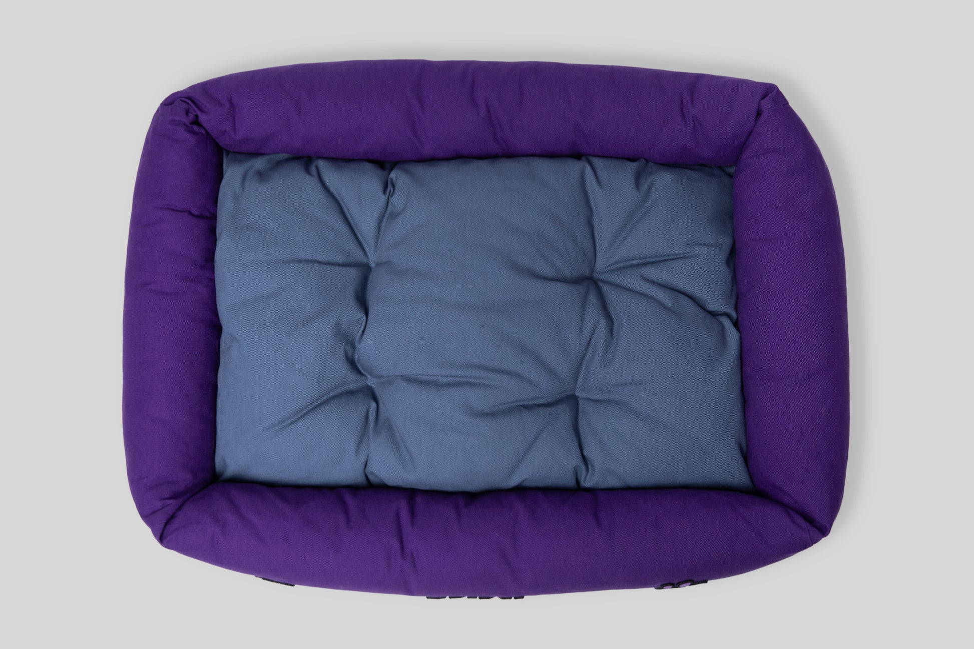 Top view of canvas cotton pet bed with tufted cushion, purple and blue colorway