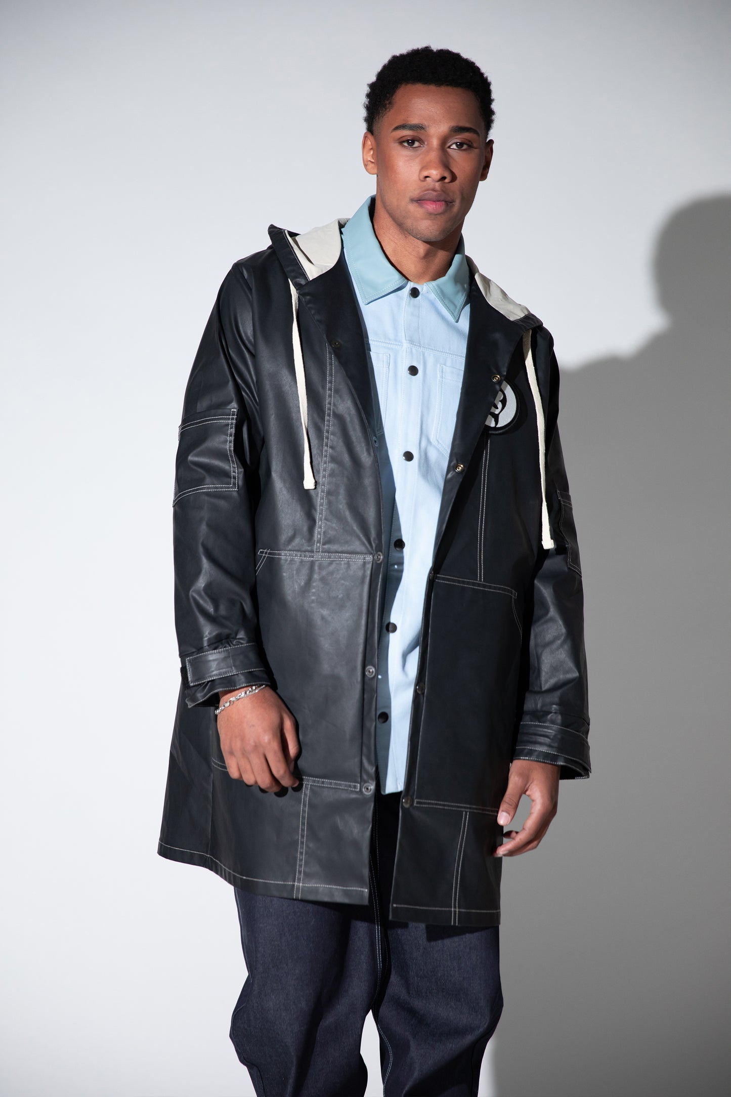Full body view of Totem coat layered over shirt, dark grey waterproof fabric