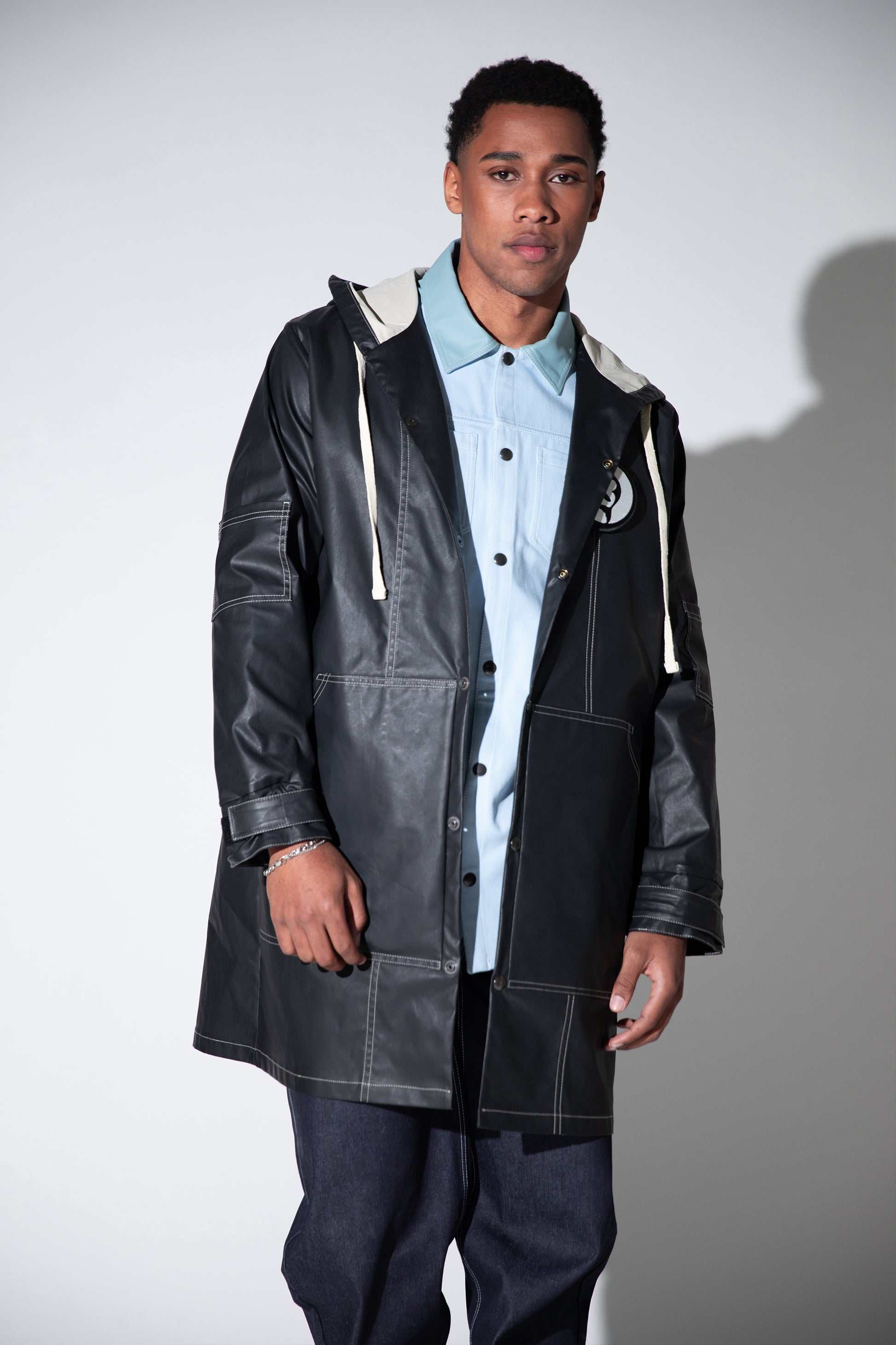 Full body view of Totem coat layered over shirt, dark grey waterproof fabric